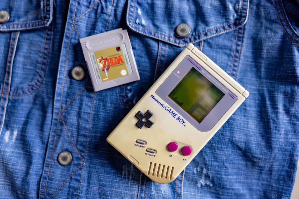 retro gaming console Nintendo Gameboy and Zelda game laid across a denim shirt